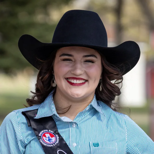 A rodeo queen in a black cowboy hat and sash, smiling